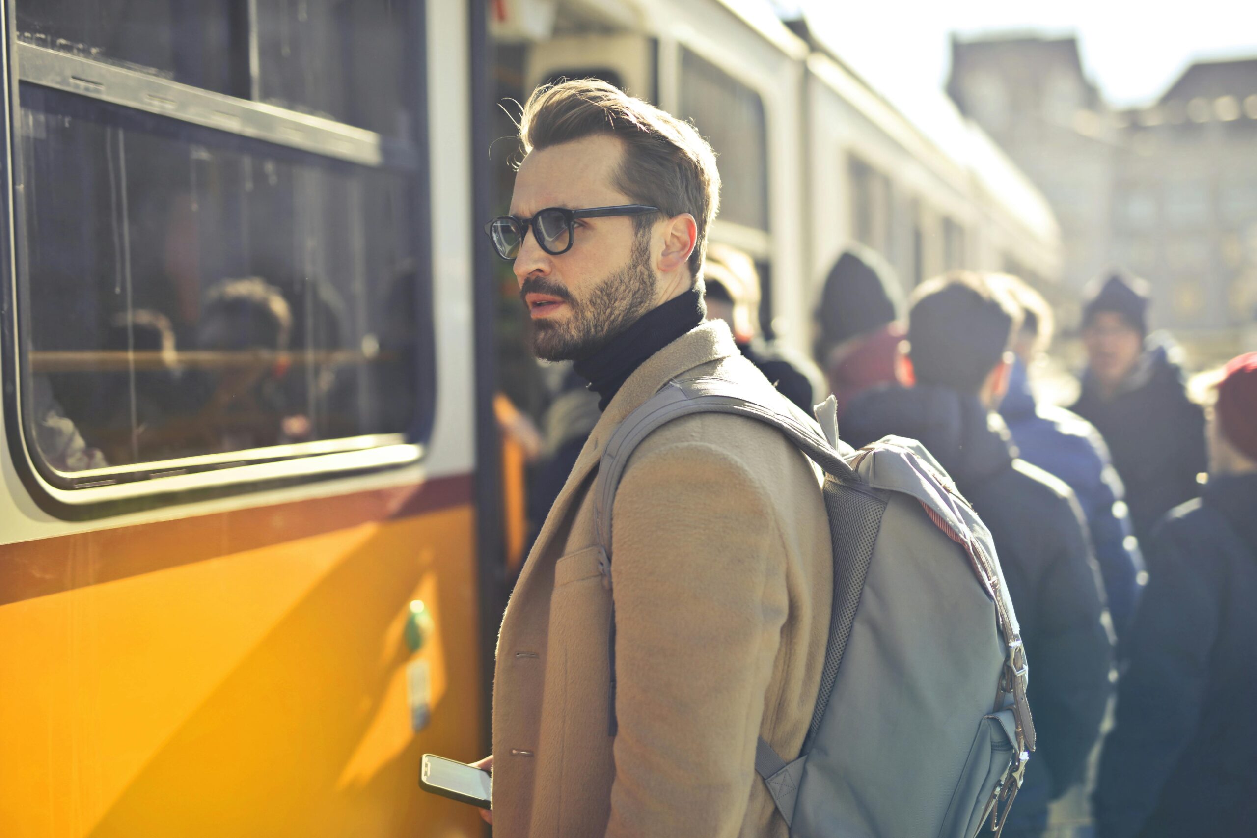 Home A stylish man with a backpack boards a tram in bustling Budapest, Hungary, during the day.